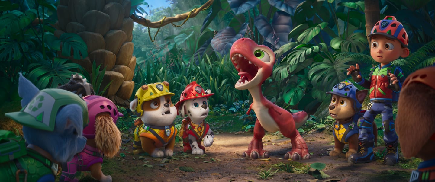 William Desrosiers as “Rocky”, Mckenna Grace as “Skye”, Lucien Duncan-Reid as “Rubble”, Carter Young as “Marshall”, Rain Janjua as “Chase”, and Henry Bolan as “Ryder” surround Rhubarb in PAW Patrol: The Dino Movie from Paramount PIctures and Spinmaster. 